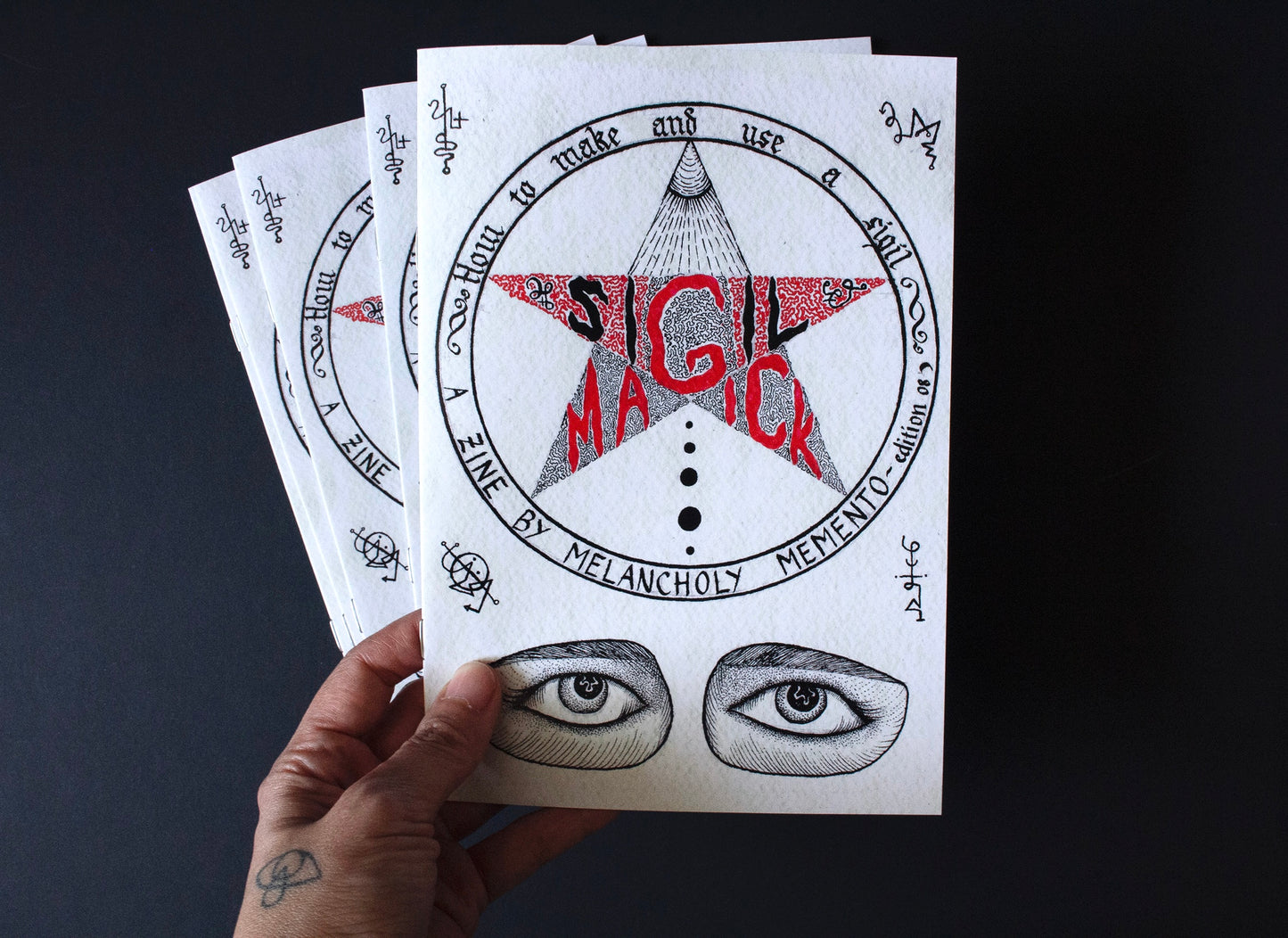 A woman’s hand holding a copy of the Sigil Magick Zine